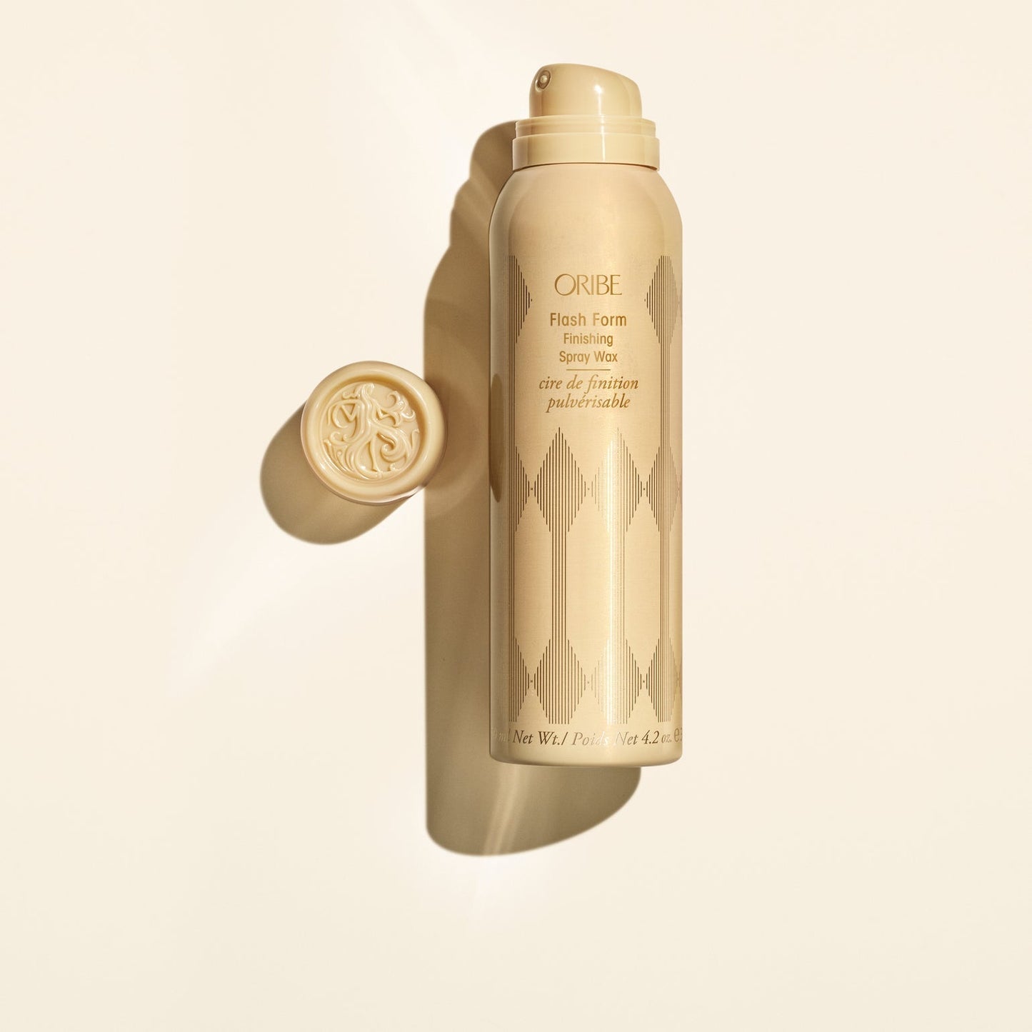 Oribe hair product spray bottle on a beige background