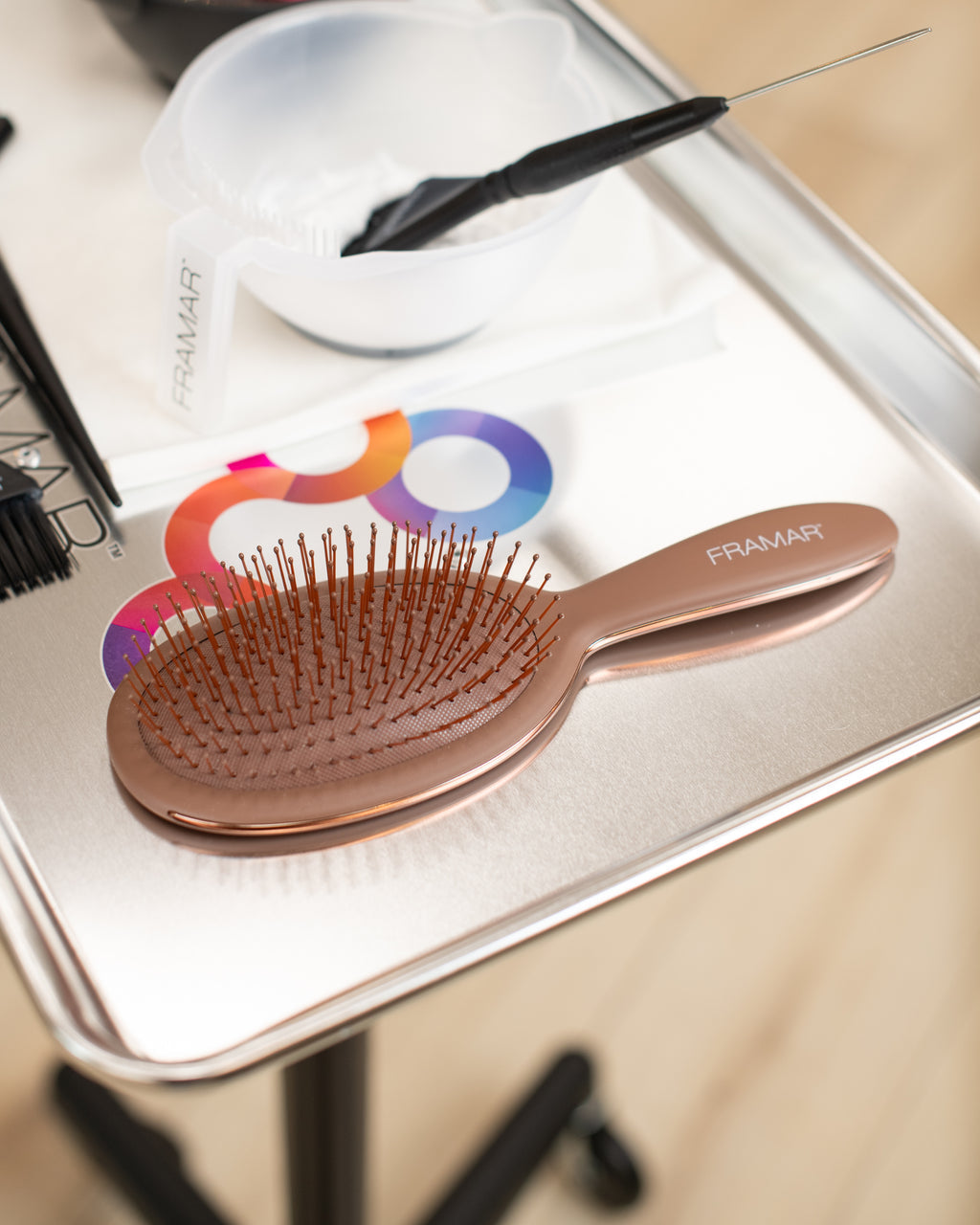 Chocolate brown hairbrush on a white surface with a colourful logo in the background