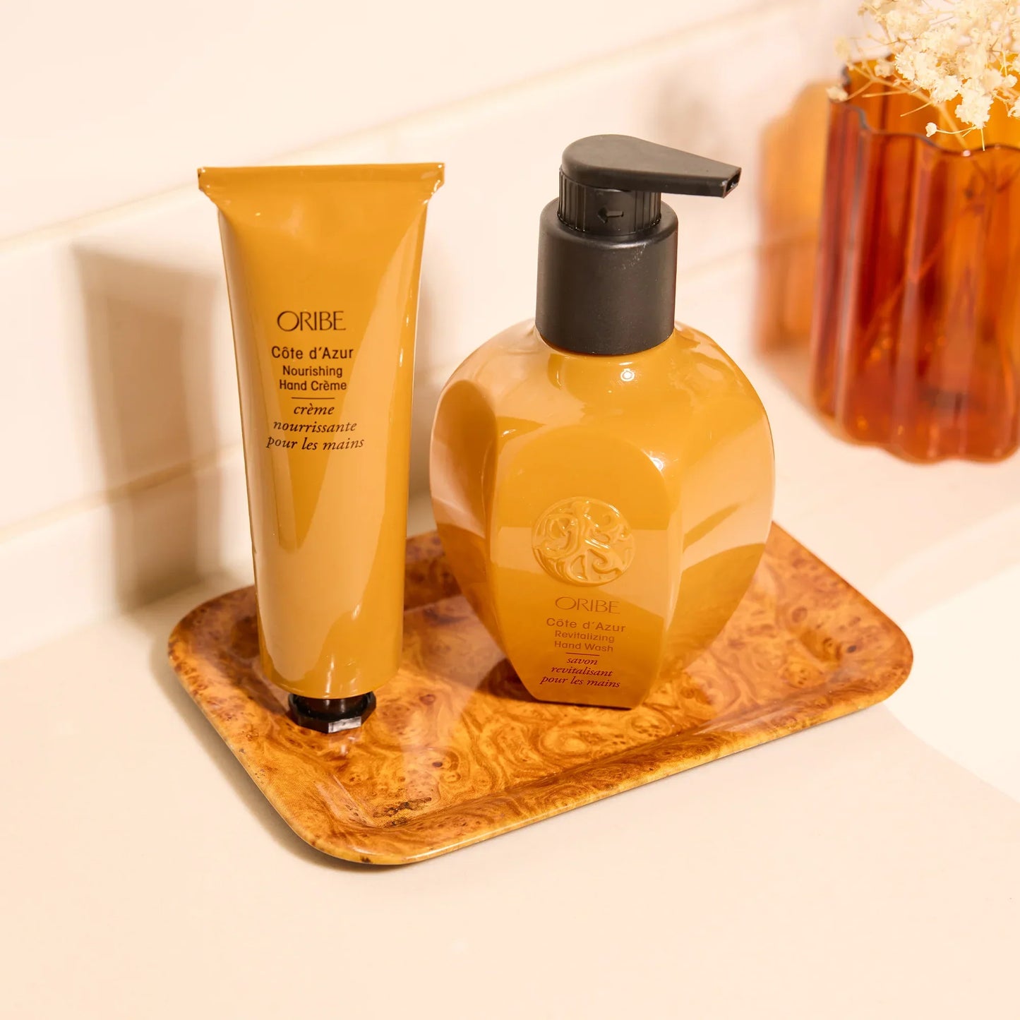 Oribe hand care products on a wooden tray with a neutral background