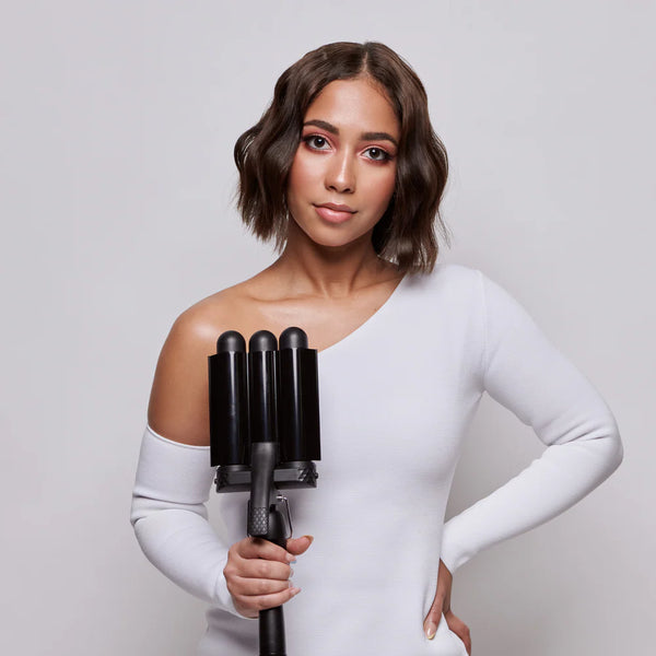 Woman holding a hair styling tool against a plain background