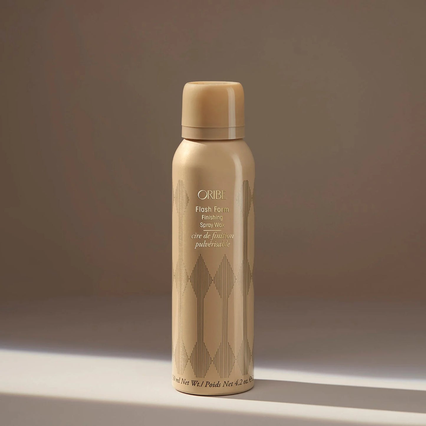 Beige hair spray bottle with 'Oribe' branding on a neutral background