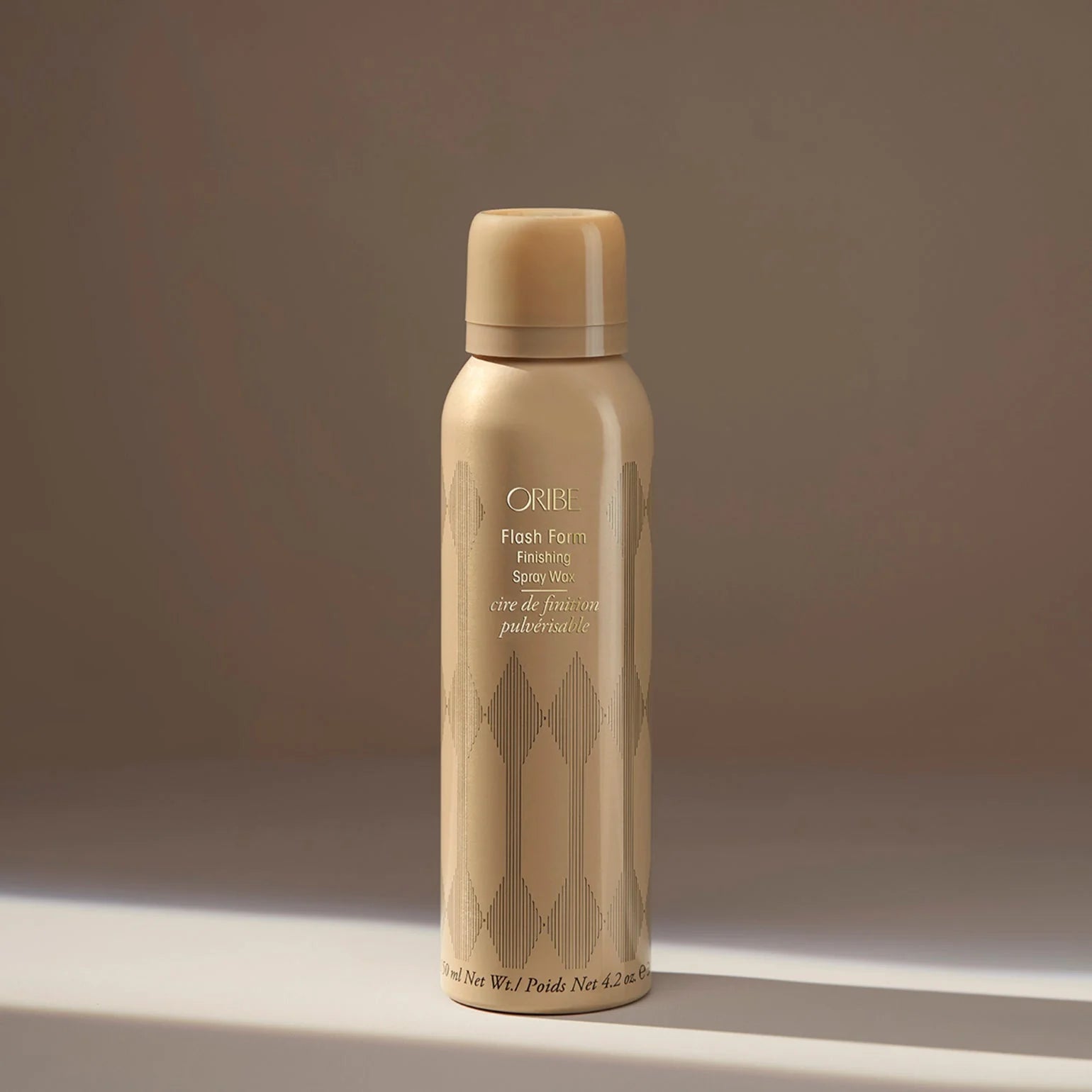 Beige hair spray bottle with 'Oribe' branding on a neutral background