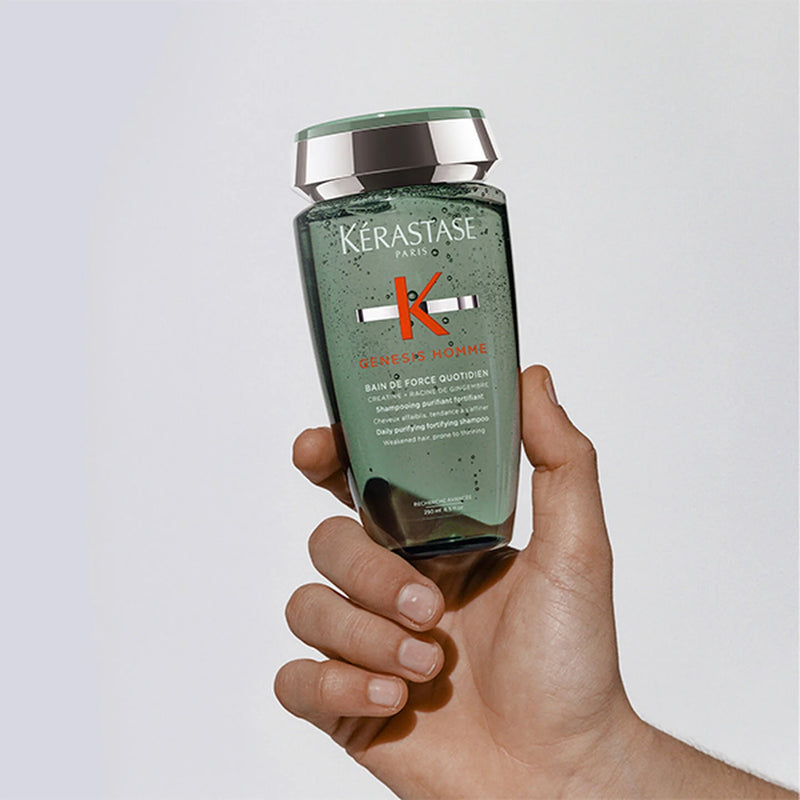 Hand holding a bottle of Kérastase shampoo against a light background