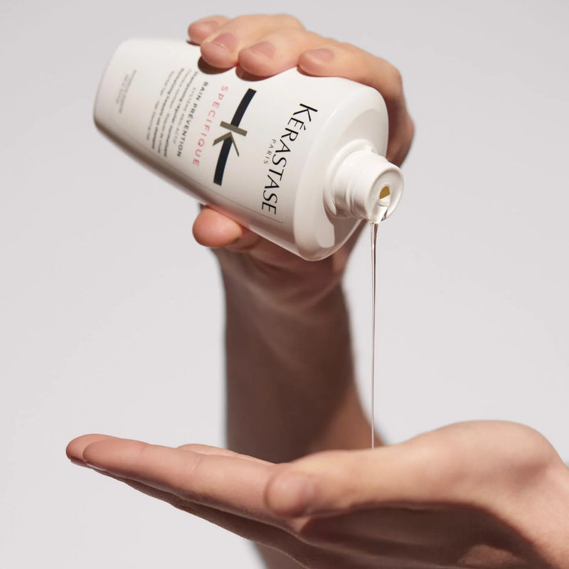 Person pouring Kérastase product into another hand against a neutral background