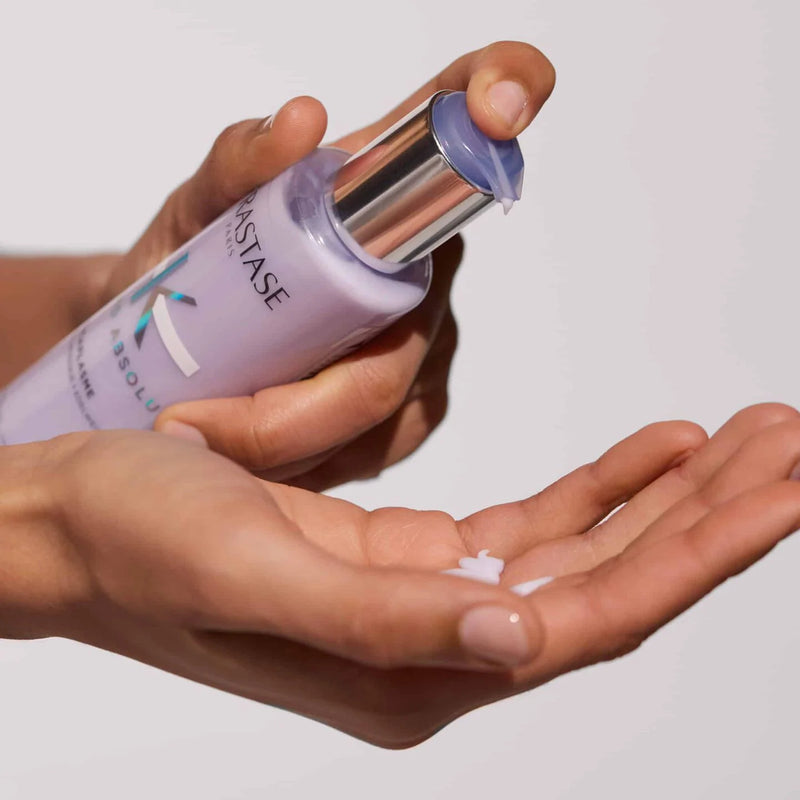 one hand holding and squeezing Kerastase cicaflash serum onto other hand