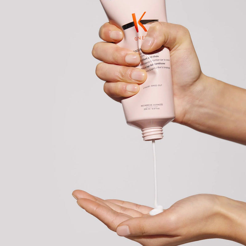Hand holding a pink skincare product with brand 'K' on a light gray background
