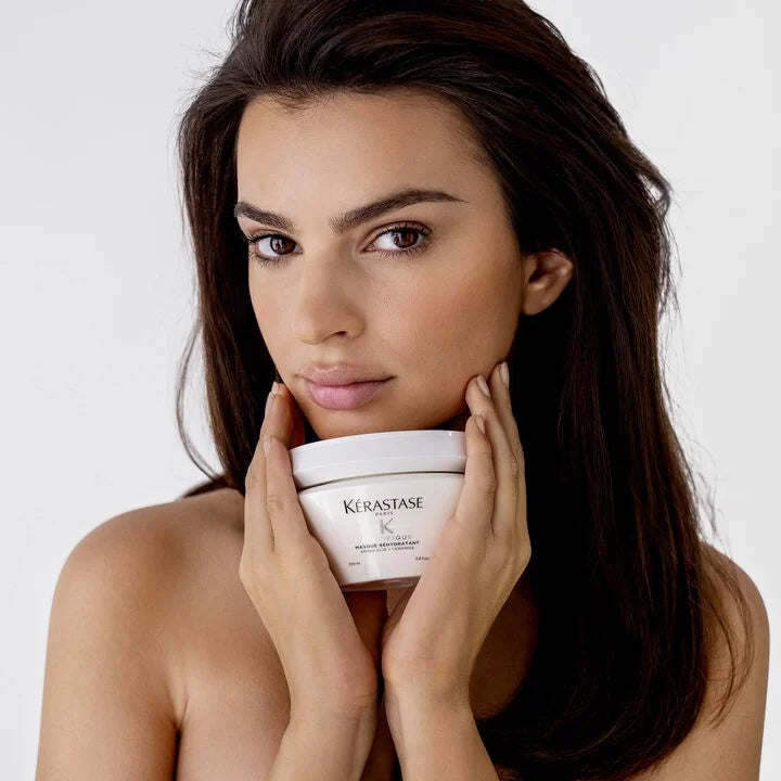 Woman holding a Kérastase product against a plain background
