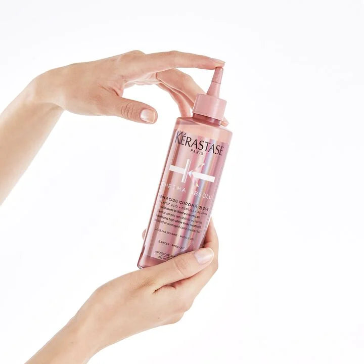 Kérastase bottle held by a hand on a white background