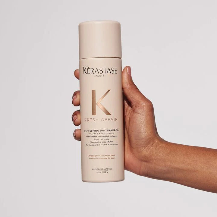 Kérastase Fresh Affair dry shampoo bottle held by a hand against a light gray background