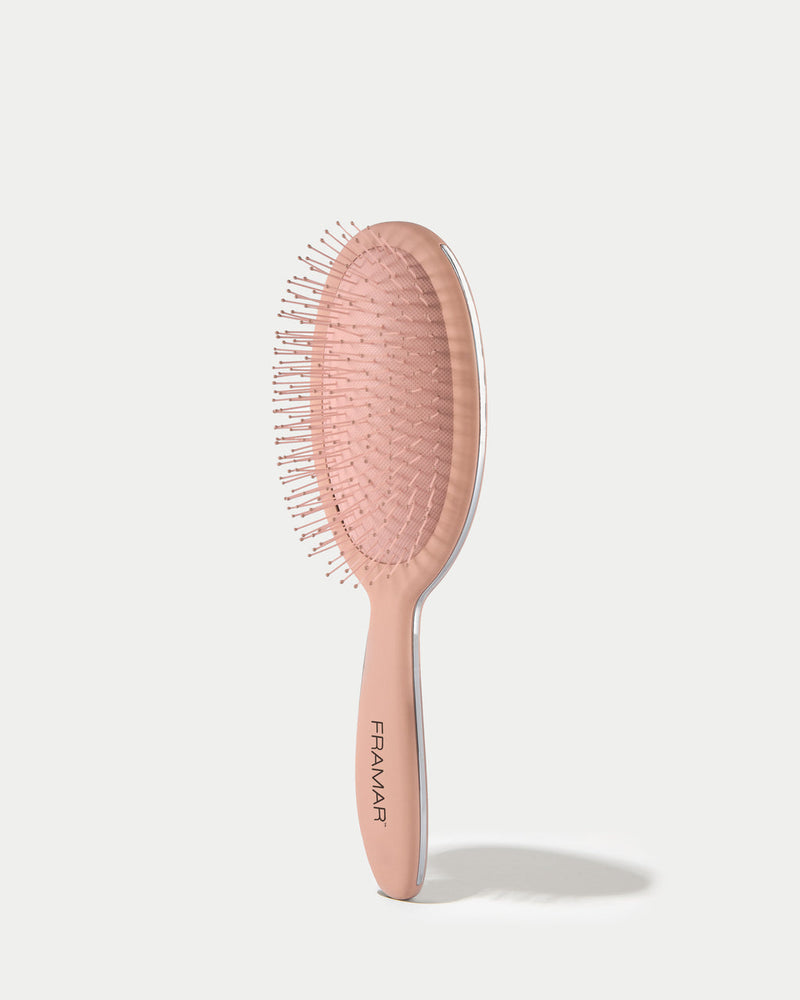 Pink hairbrush with 'FRAMAR' branding on a light grey background