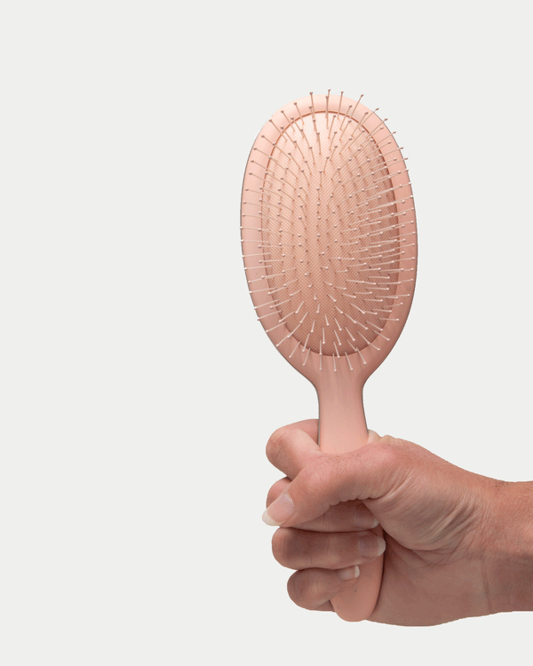Hand holding Framar Detangling Brush Champagne colour and moving