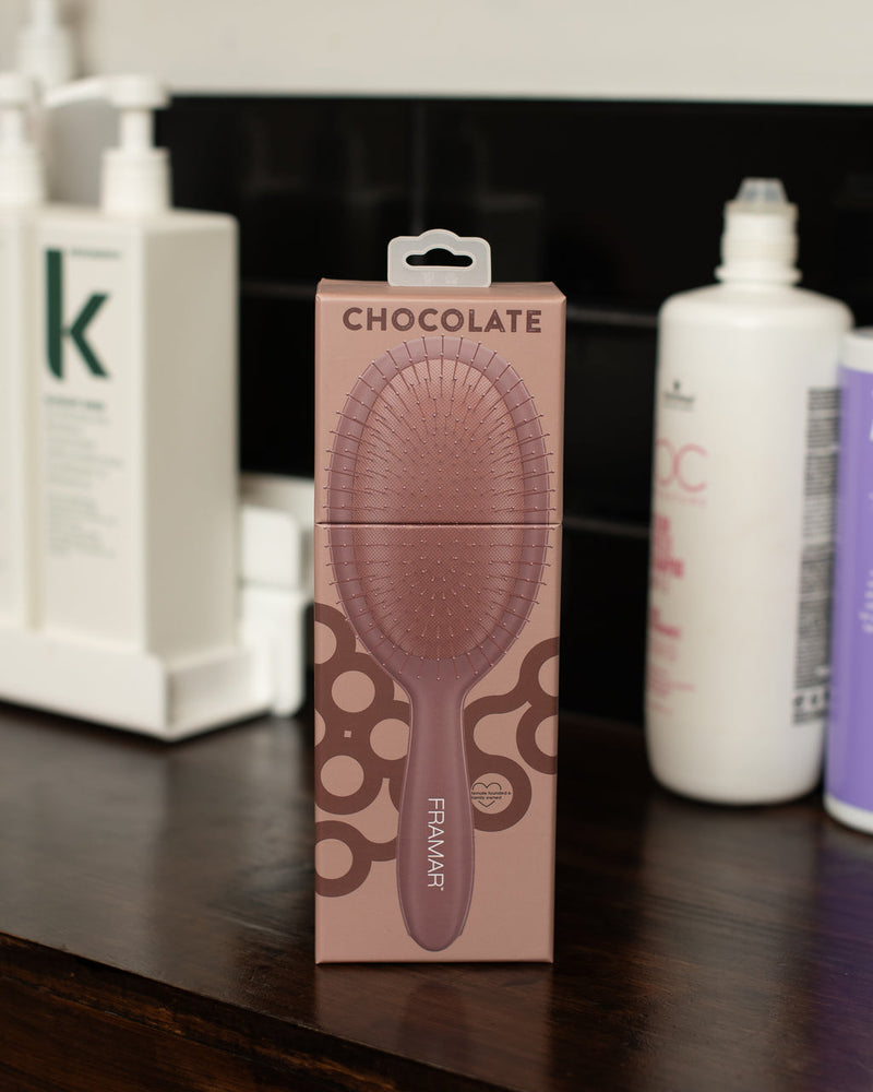 Pink hairbrush packaging with 'Chocolate' branding on a dark surface.