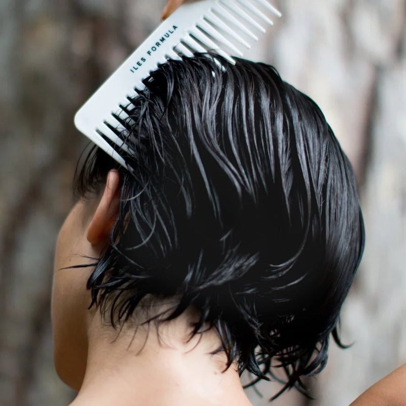 Person combing their black hair with a comb.
