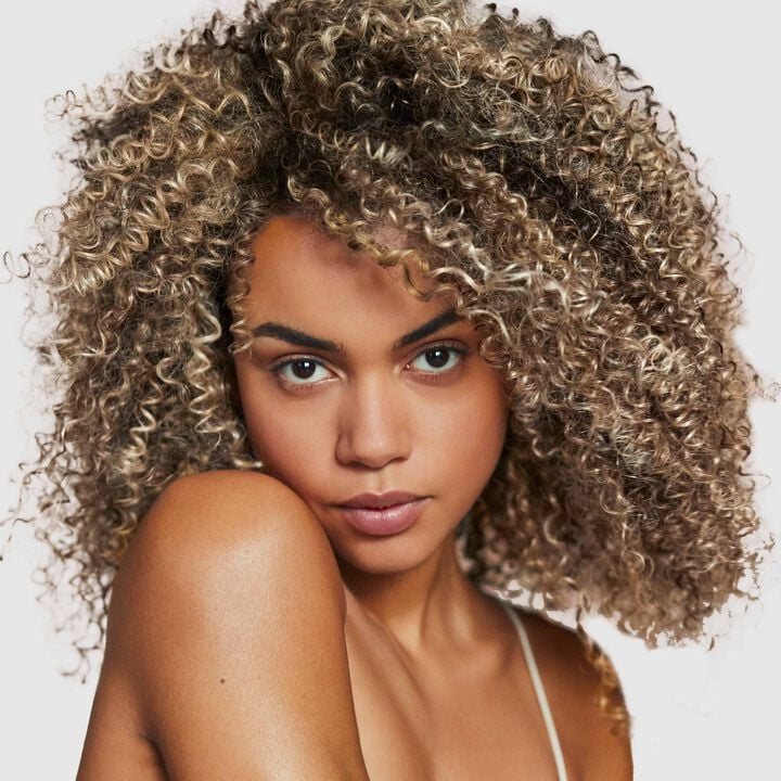 Woman with voluminous curly hair on a plain background