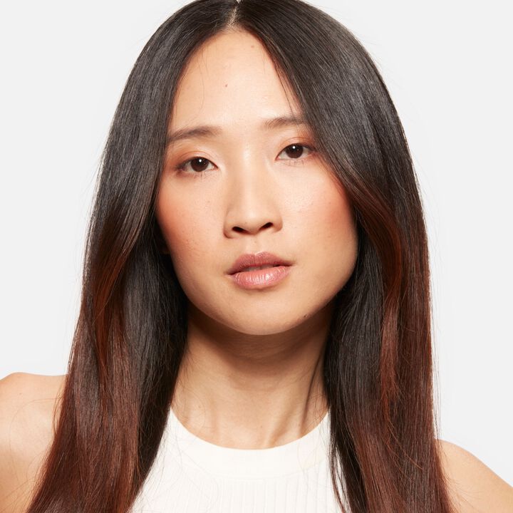 Woman with long dark hair against a plain background