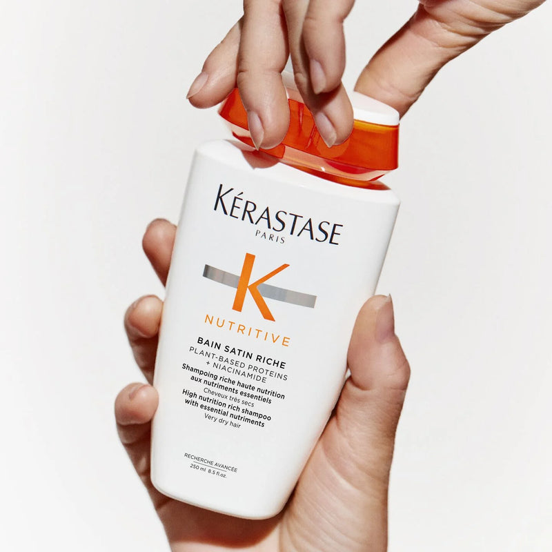 Kérastase Nutritive shampoo bottle held by a person with a white background