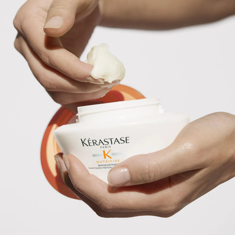 Kérastase hair care product with a hand holding it against a neutral background