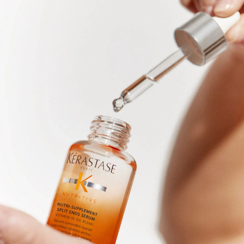 Kerastase Nutritive Nutri-Supplement Split-Ends Serum bottle with fingers holding on pipette on white background