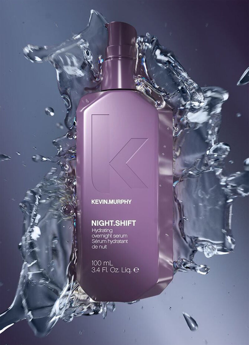 Kevin Murphy Night Shift serum bottle surrounded by water splashes on a dark background