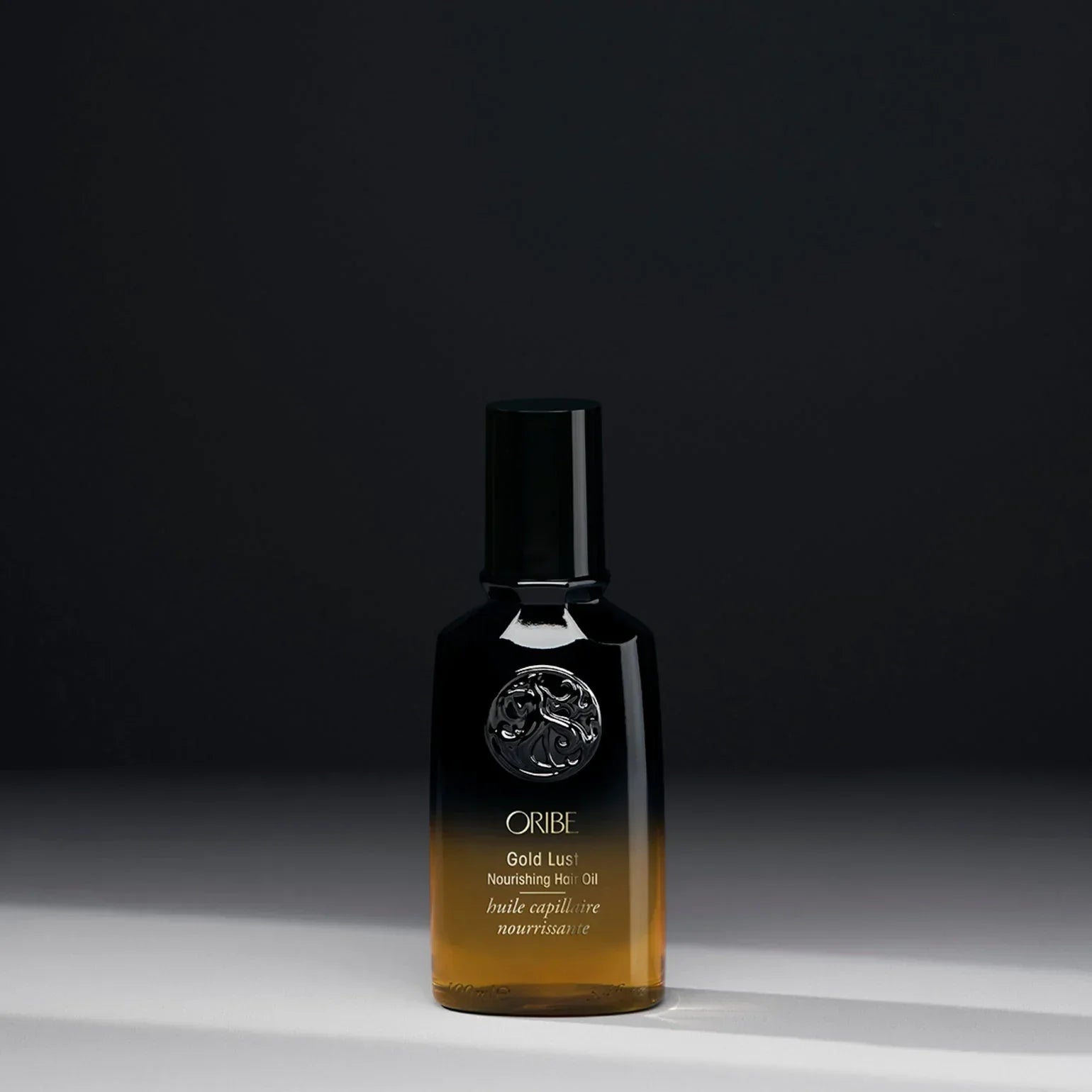 Oribe Gold Lust nourishing hair oil bottle on a dark background