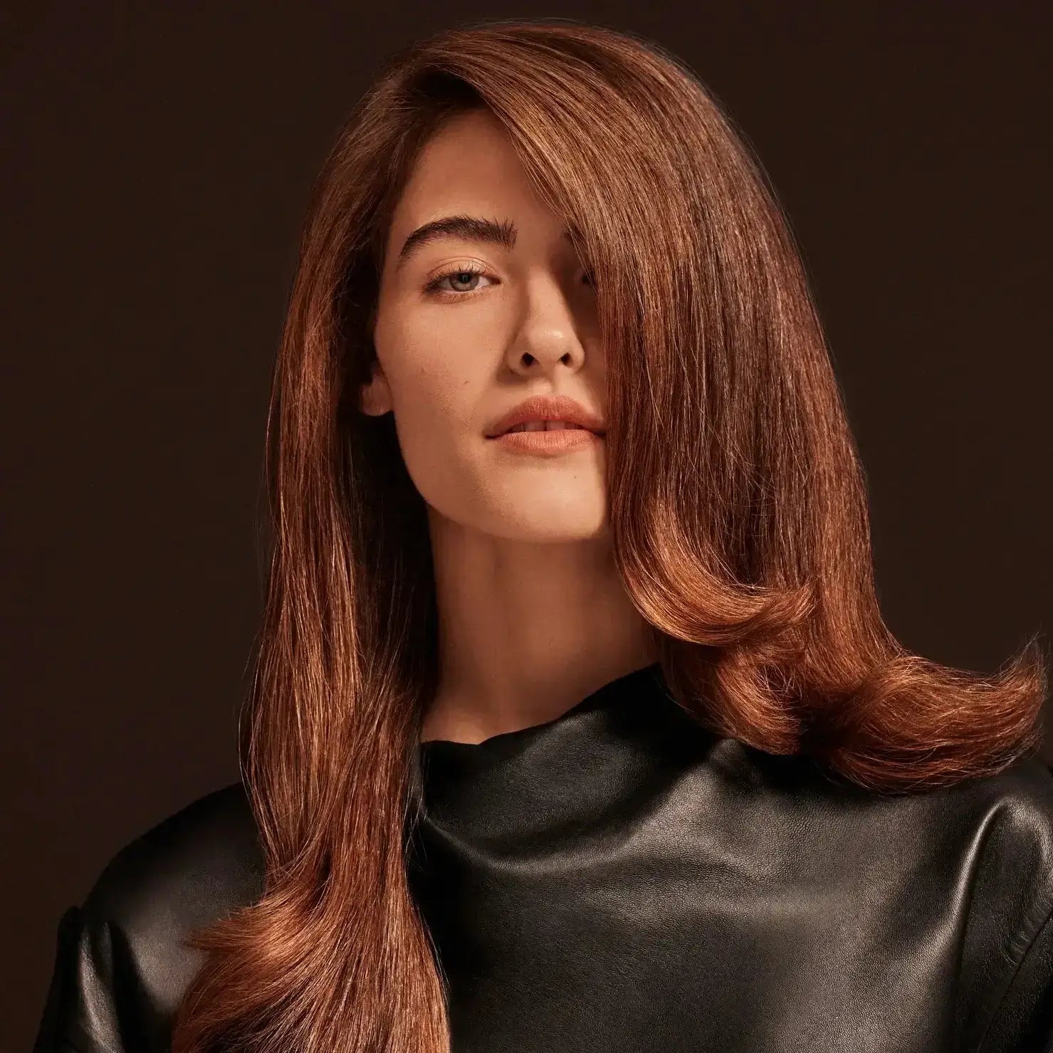 Chestnut brown hair woman with brown background and black leather top