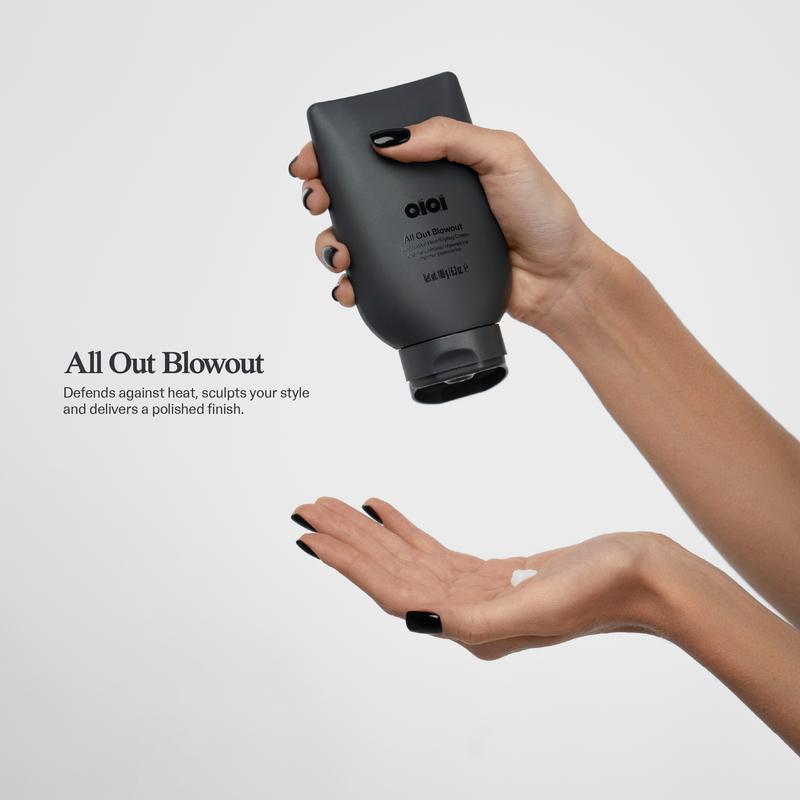 Hand holding a black bottle labeled 'OIQI' with a small amount of product on an open palm against a light grey background.