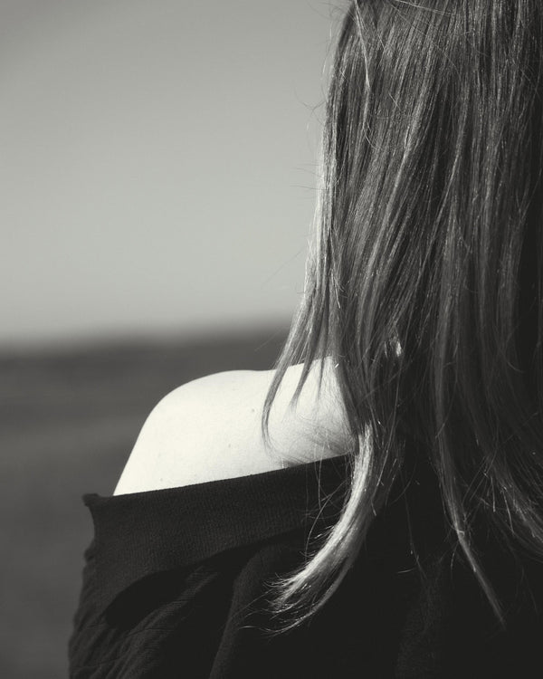 Black and white photo of a person with long hair looking away from the camera.