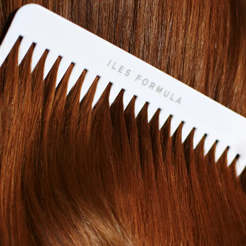 Close-up of a comb with brown hair extensions and 'ILES FORMULA' branding.