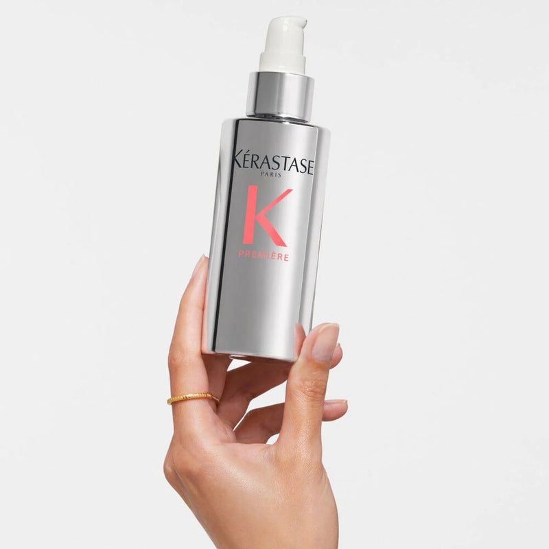 Kérastase serum bottle held by a hand on a light gray background