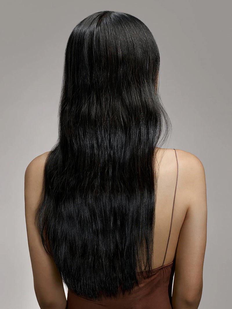 Woman with long, straight black hair against a gray background
