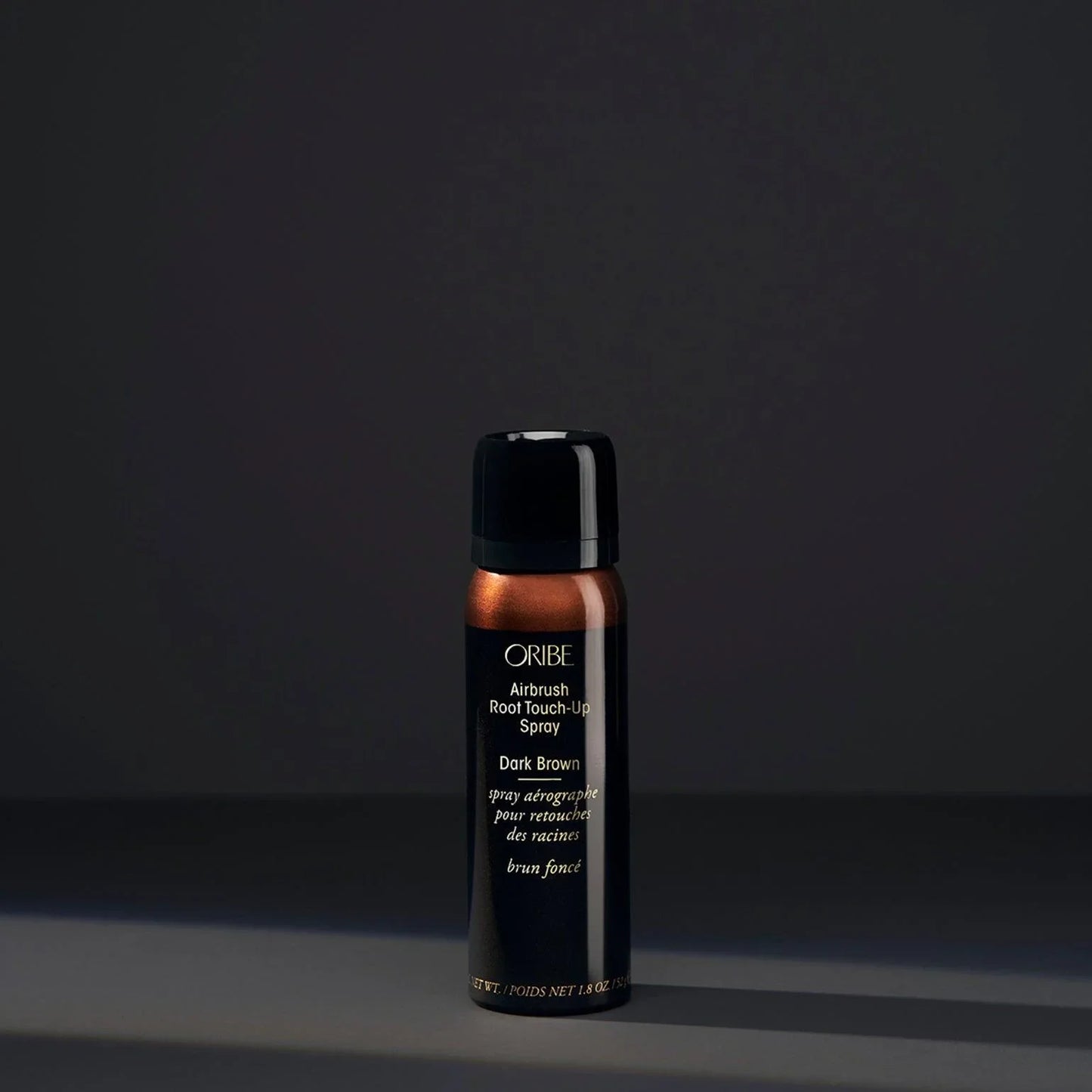 A spray bottle of Oribe Airbrush Root Touch-Up Spray in Dark Brown, designed for covering greys and roots or refreshing highlights.