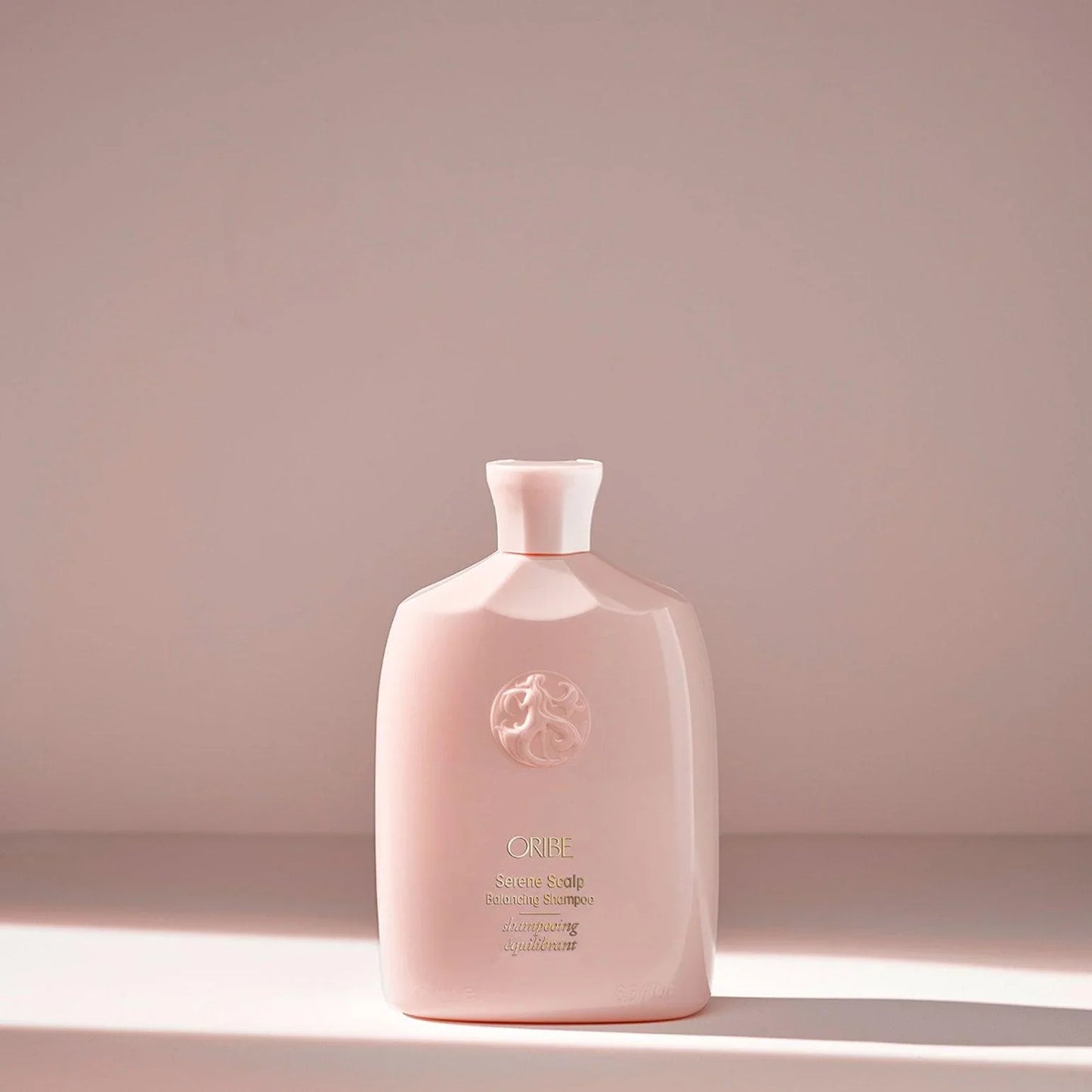A pink bottle of ORIBE Serene Scalp Balancing Shampoo against a plain background.