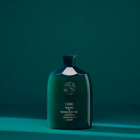 Green bottle of Oribe Shampoo for Moisture and Control with green background.