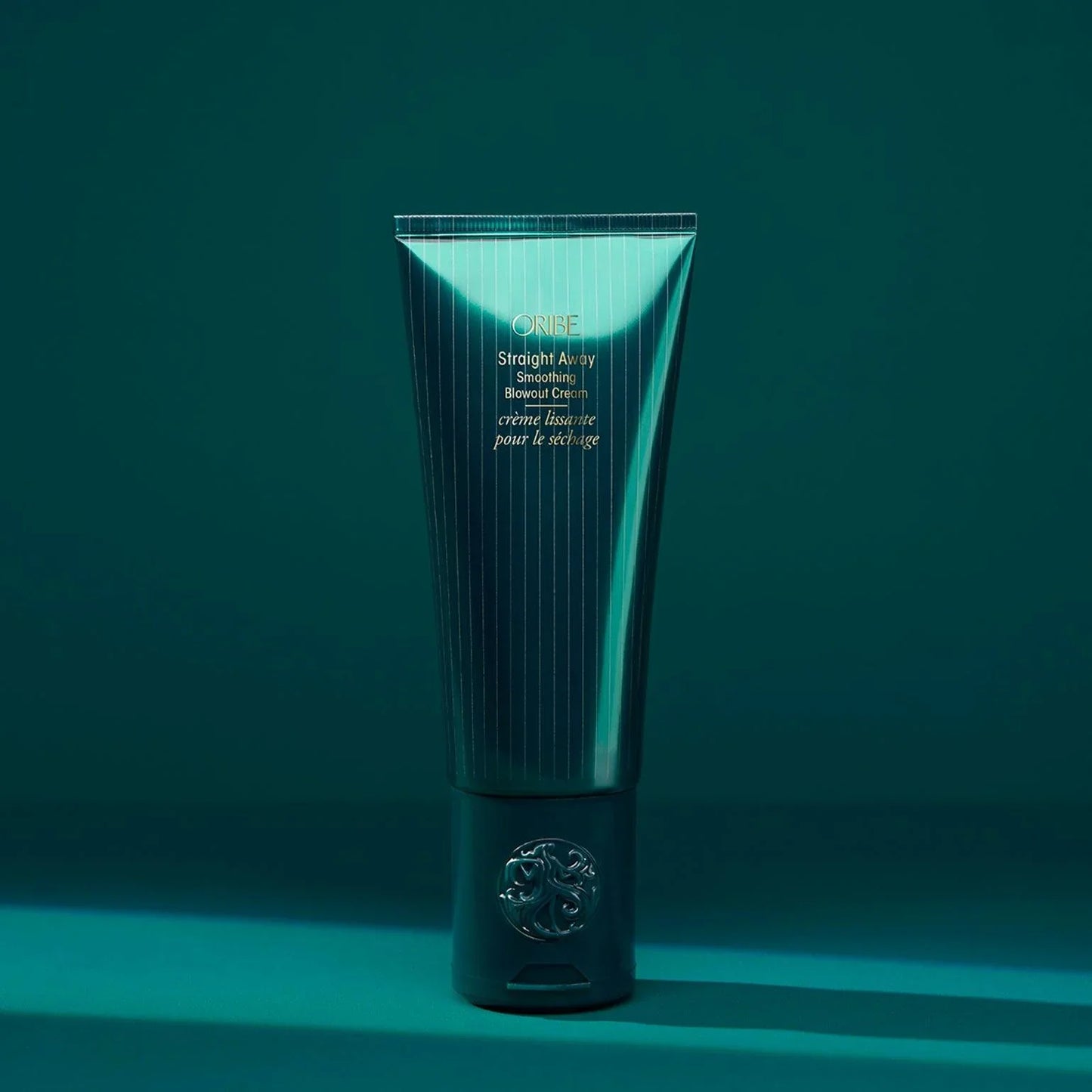 ORIBE Straight Away Smoothing Blowout Cream green bottle on green background