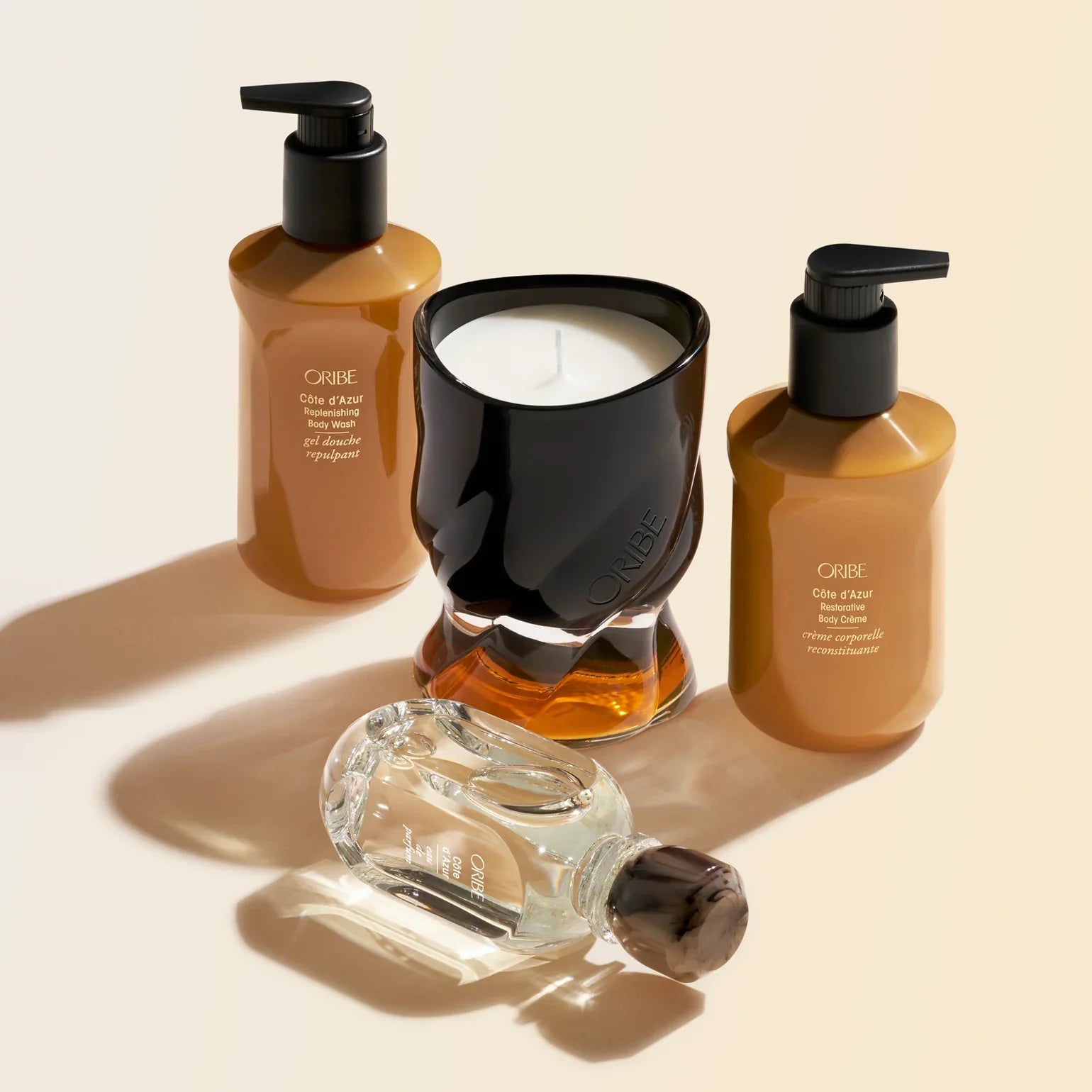 Collection of Crème de la Mer skincare products including a bottle, jar, and candle on a beige background.
