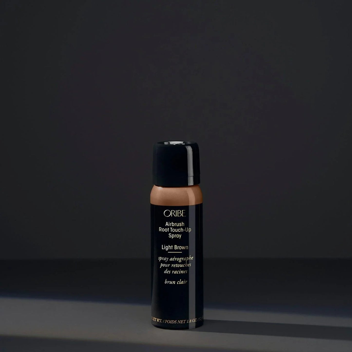 A spray bottle of Oribe Airbrush Root Touch-Up Spray in Light Brown, designed for covering greys and roots or revive highlights.