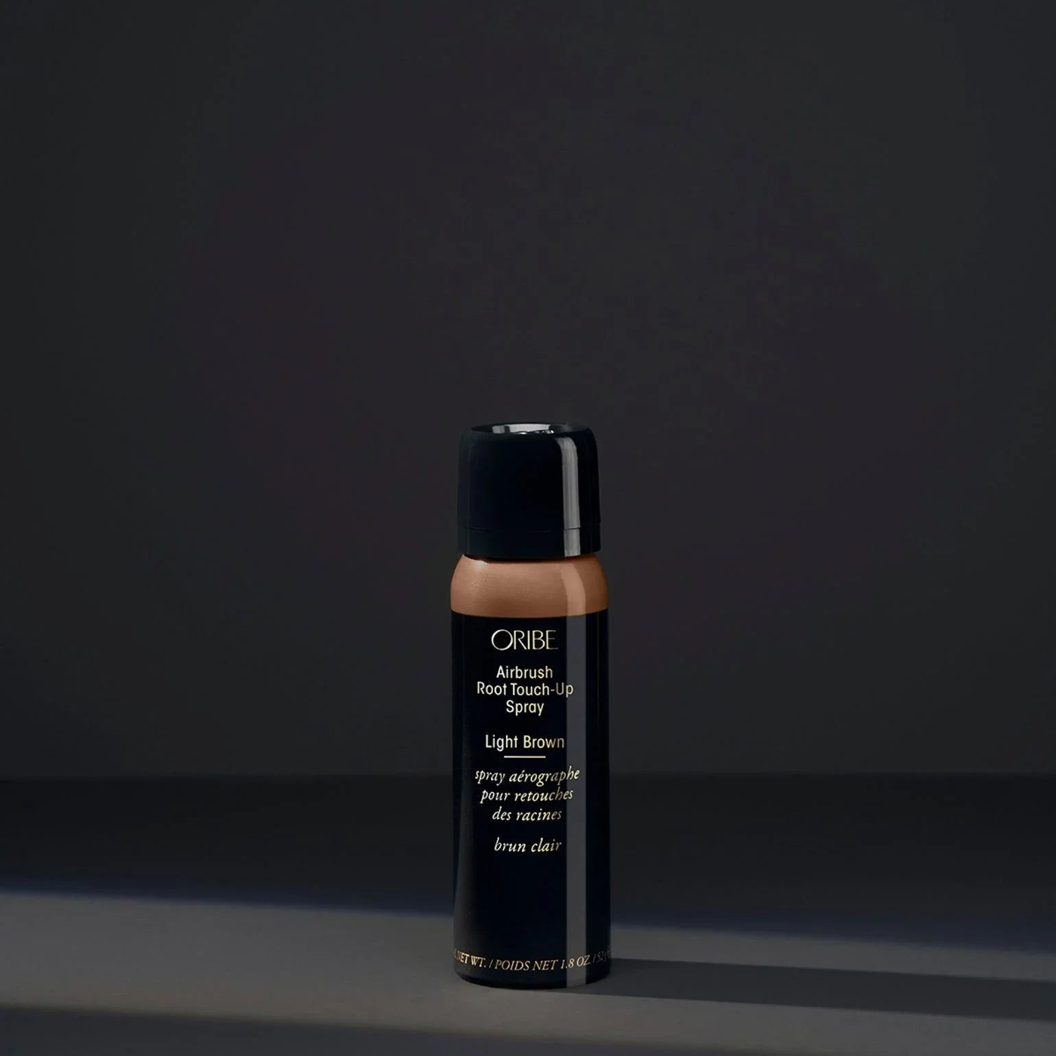 A spray bottle of Oribe Airbrush Root Touch-Up Spray in Light Brown, designed for covering greys and roots or revive highlights.